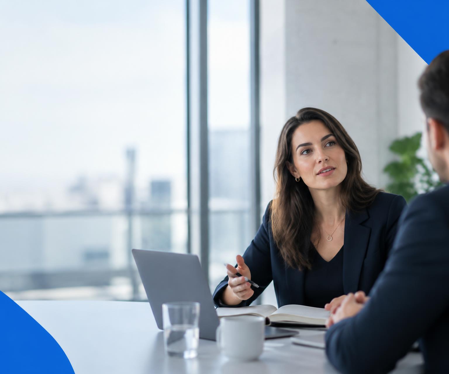 Two business professionals having a focused one-to-one conversation in a bright office, shown as an illustrative scene.